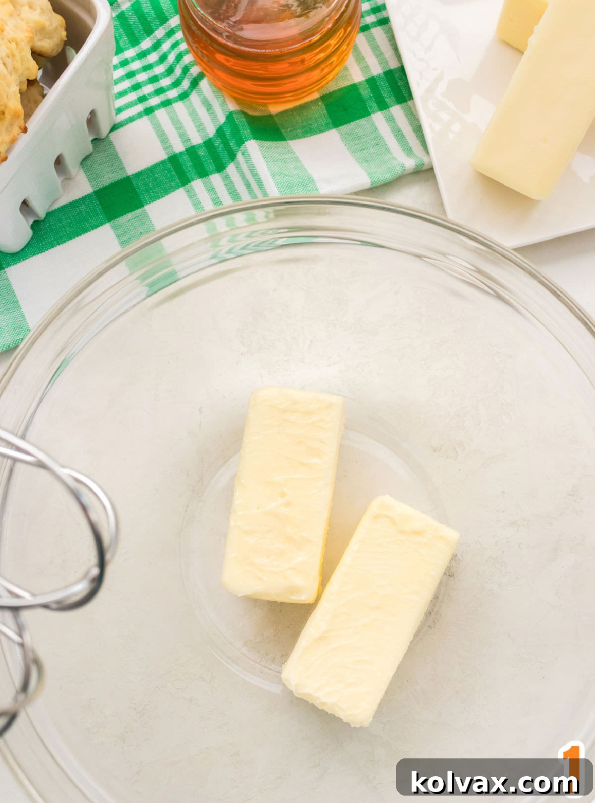 Overhead shot of a clear glass bowl with two sticks of butter in it.