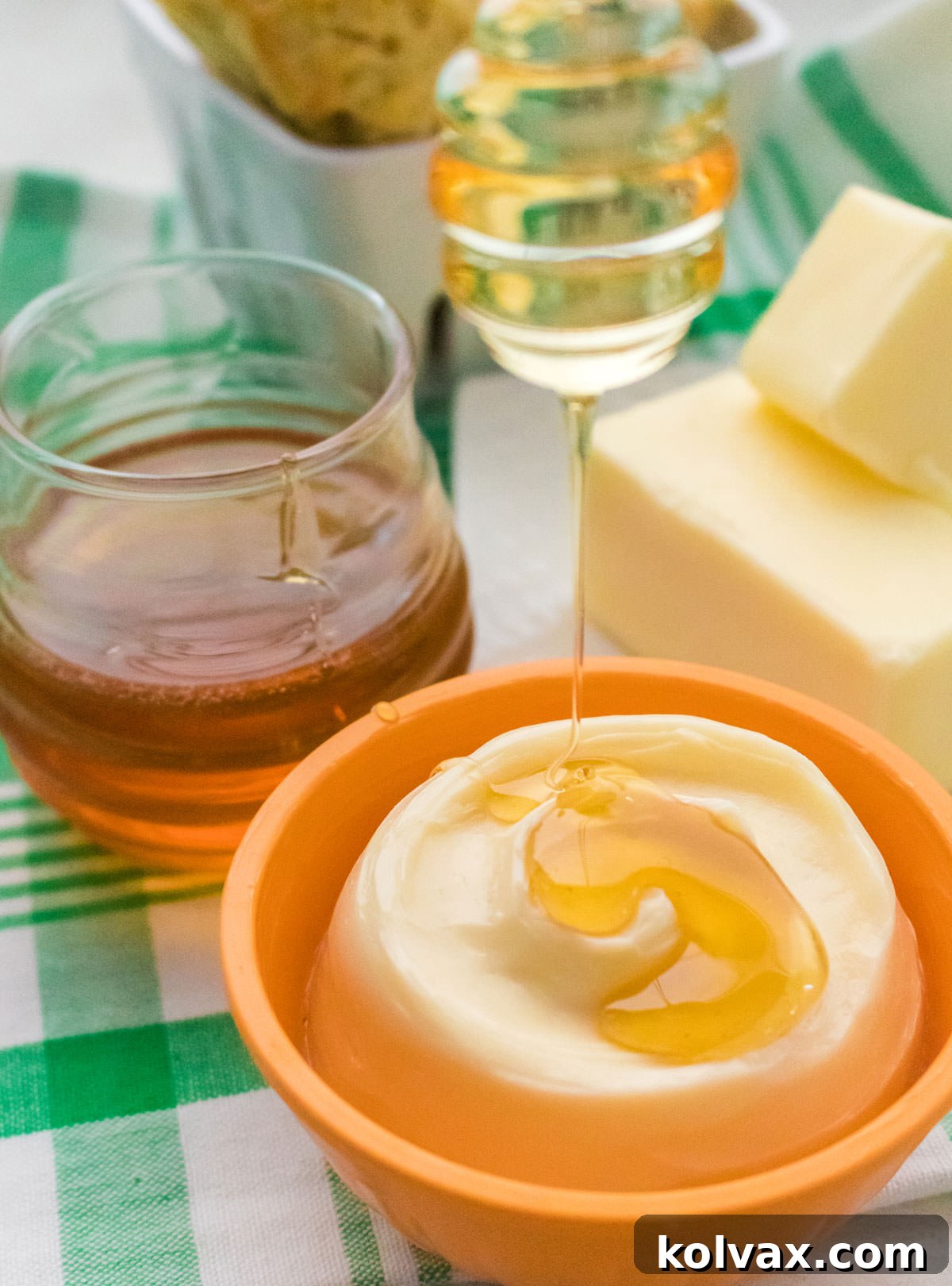 Closeup on a orange ramekin filled with Honey Butter with honey dripping down on to the honey.