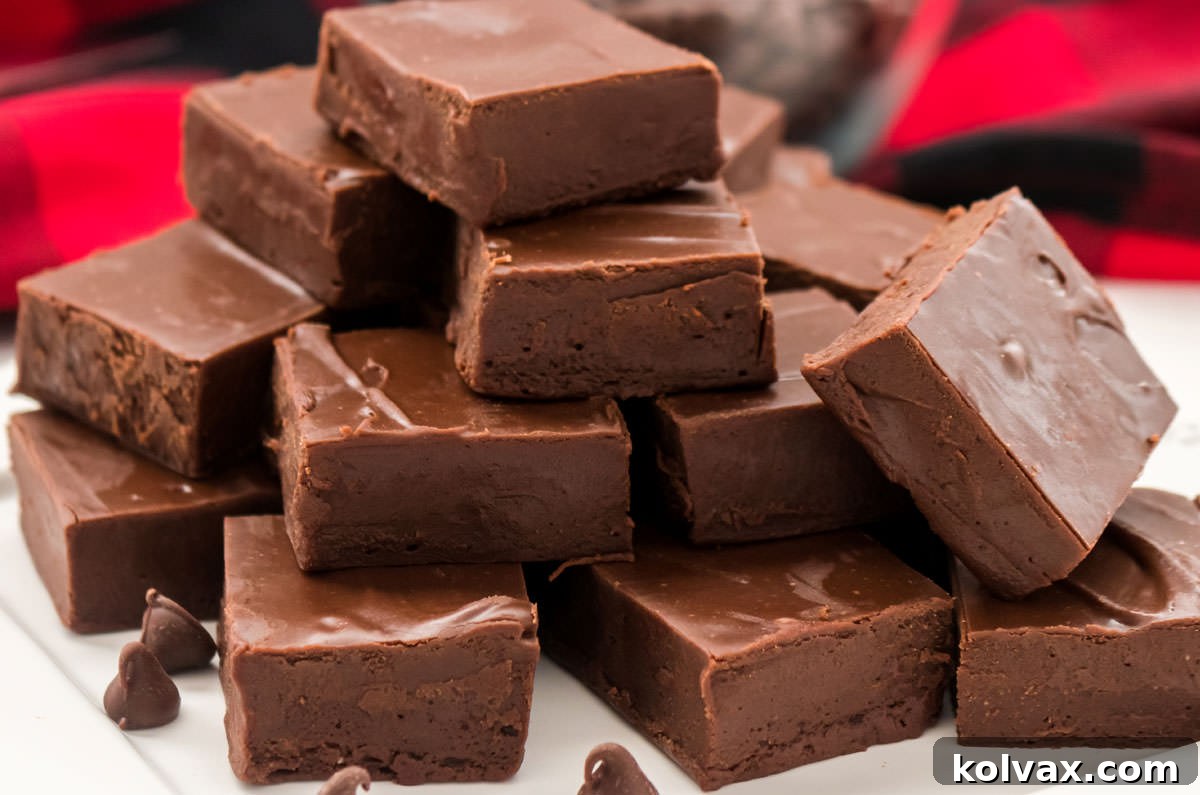 Closeup on a white plate filled with stacks of Easy Chocolate Fudge sitting in front of a red buffalo check cloth.