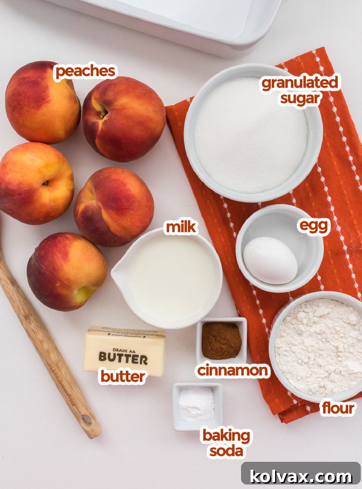 Heirloom Peach Cobbler 3 All the ingredients neatly laid out on a rustic surface, essential for making this Old Fashioned Peach Cobbler, including fresh peaches, granulated sugar, a large egg, milk, all-purpose flour, ground cinnamon, baking soda, and a stick of butter.