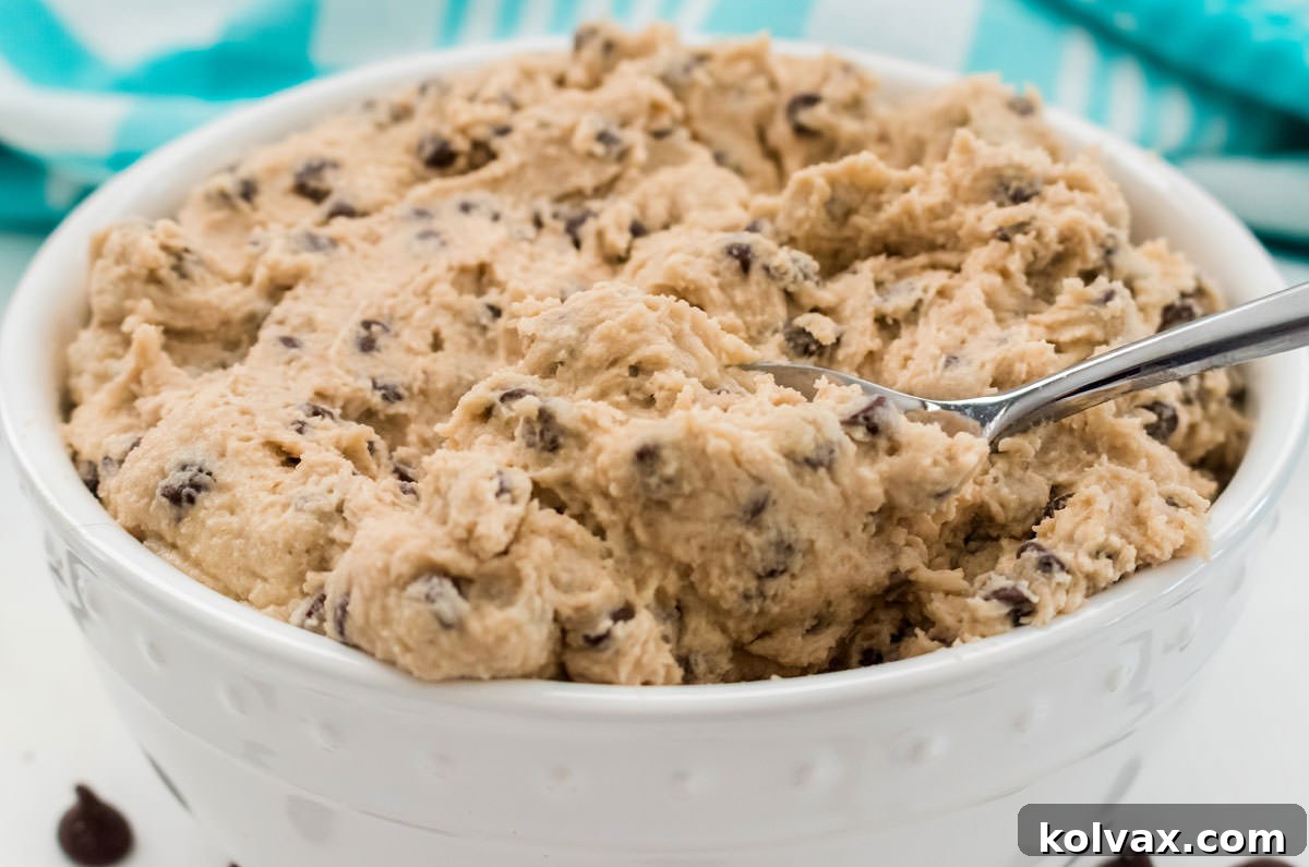Closeup on a white bowl filled with Edible Cookie Dough with a spoon in it.