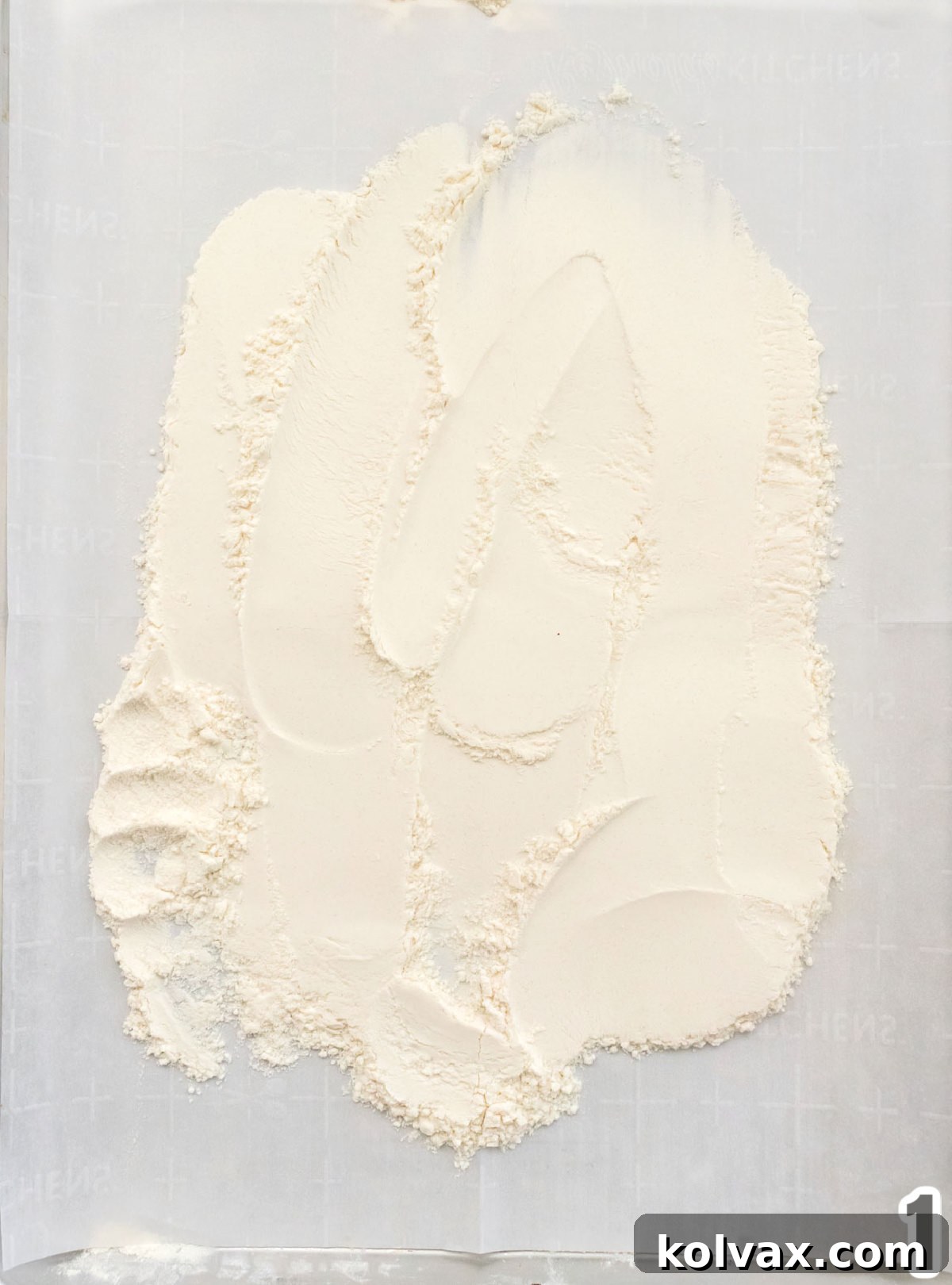 Overhead shot of a cookie sheet, lined with parchment paper, evenly covered in a layer of flour ready for heat treatment.