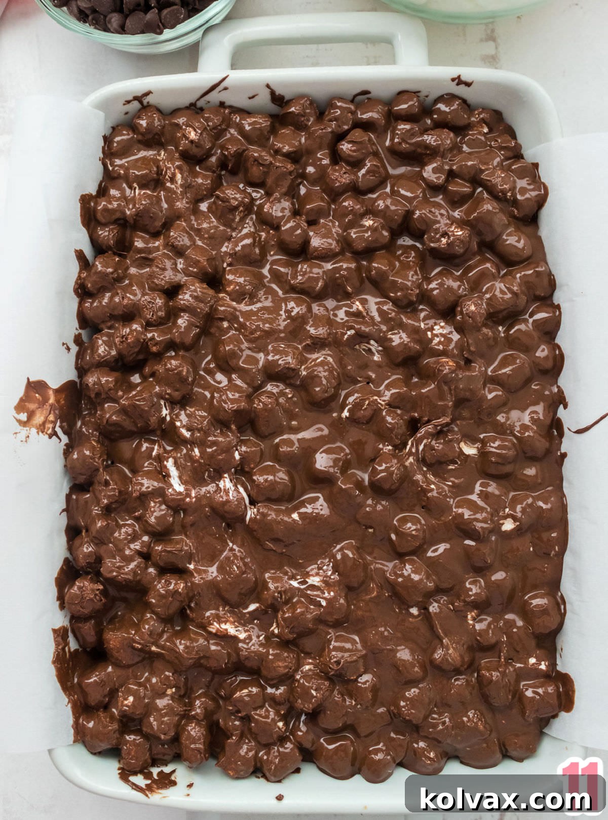 An overhead shot showing the warm chocolate marshmallow mixture being poured evenly over the chilled graham cracker crust in a 9x13 inch baking dish.