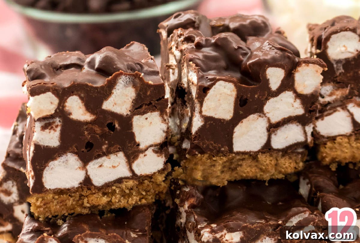 A closeup of two perfectly cut Chocolate Marshmallow Bars resting on a mound of other cookie bars, highlighting their appealing layers and texture.