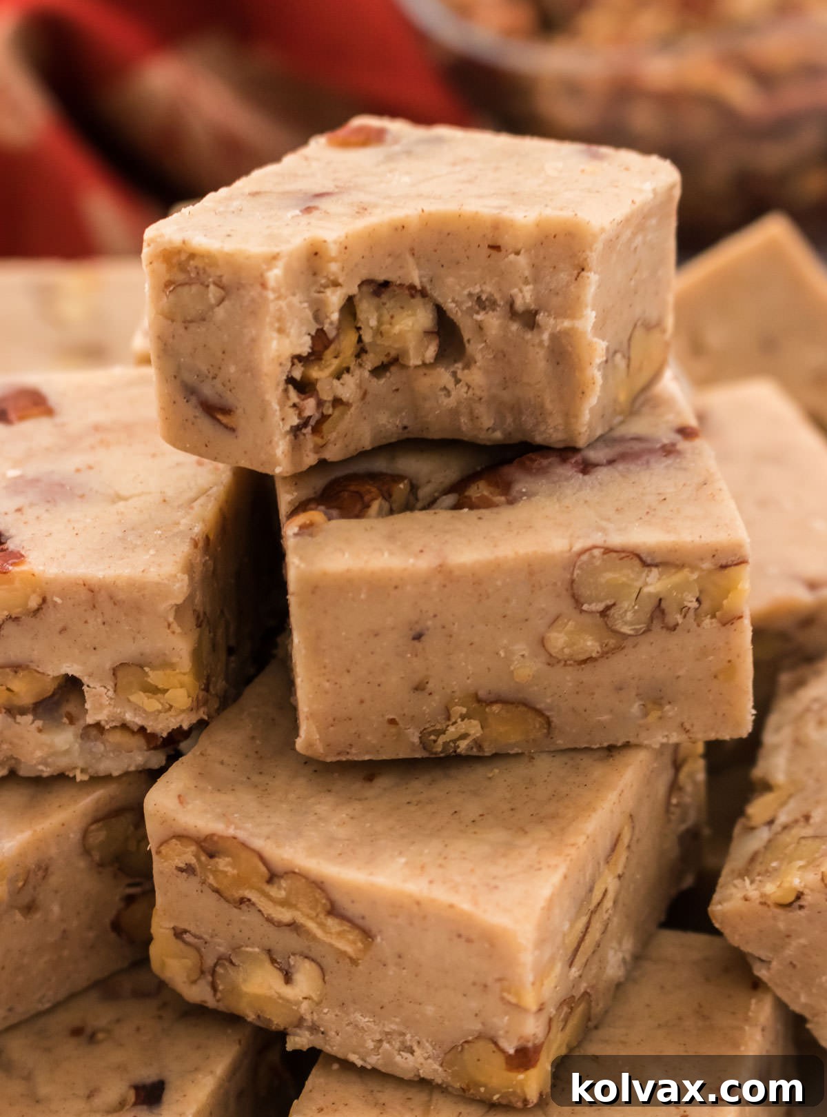 A close-up shot of a stack of Butter Pecan Fudge pieces, with one piece having a bite taken out of it, showing the creamy texture and pecan bits.