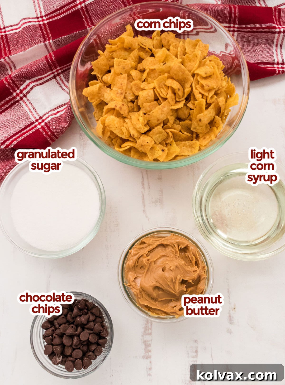 A flat lay of all necessary ingredients: a bag of Fritos Corn Chips, granulated sugar, light corn syrup, creamy peanut butter, and a bowl of chocolate chips.