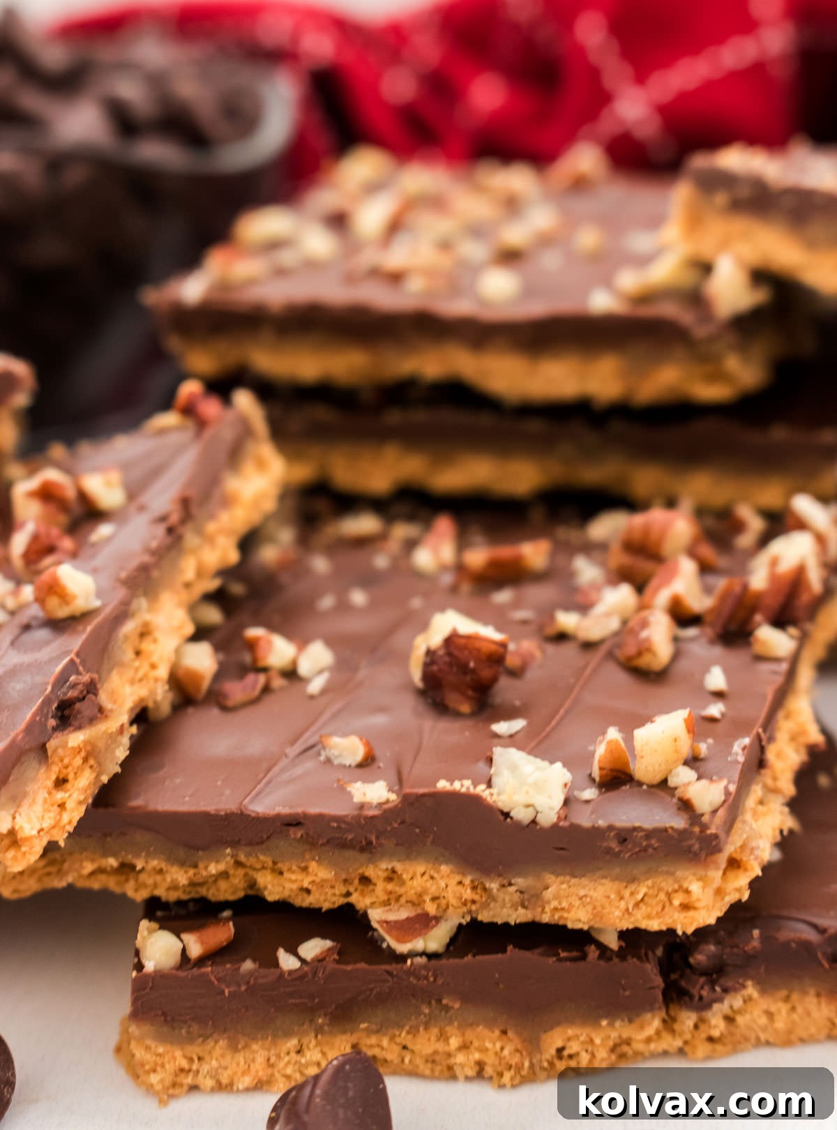 Closeup on a stack of Graham Cracker Toffee pieces arranged on a white surface in front of a red kitchen towel.
