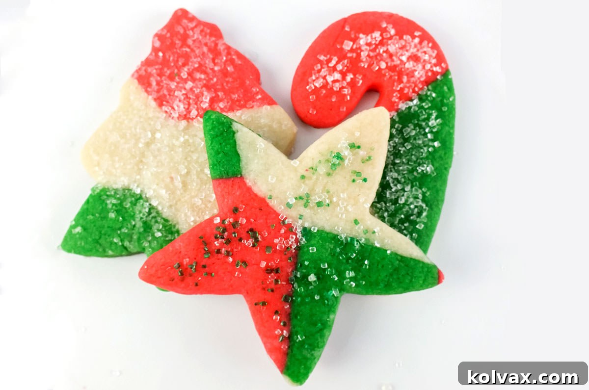 Three colorful Christmas Marble Sugar Cookies displaying intricate red, green, and white swirls, arranged neatly on a pristine white surface.