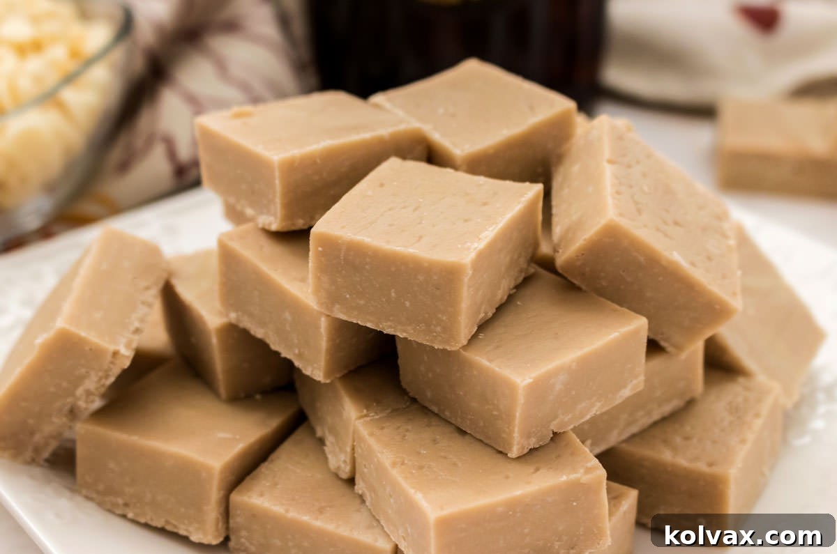 Closeup on a white serving platter filled with a stack of Maple Fudge sitting on a white table with a Fall Table Linen in the background.