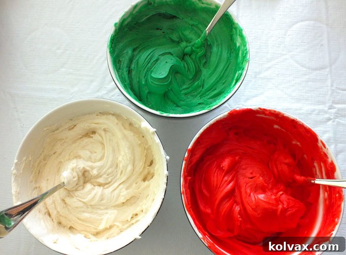 Bowls of vibrant red, green, and white buttercream frosting, ready for Christmas cookie decorating