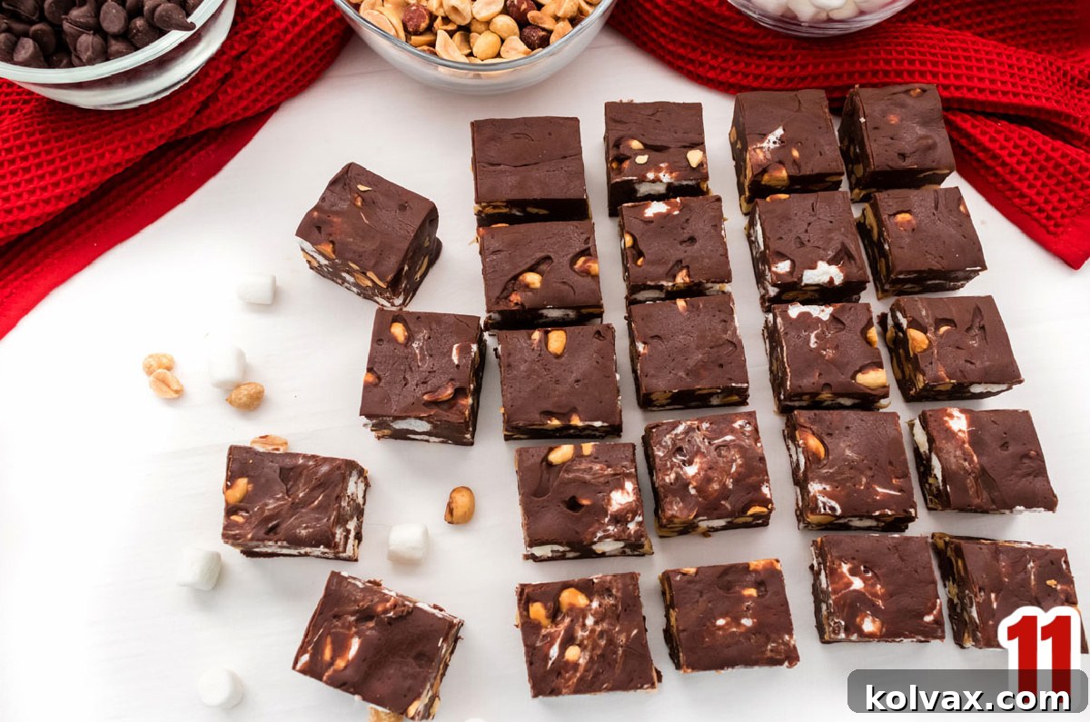 Decadent Rocky Road Bliss 7 An overhead shot showcasing beautifully arranged squares of Rocky Road Fudge, perfectly cut and lined up in rows on a crisp white surface, surrounded by loose peanuts and mini marshmallows, ready for serving or gifting.
