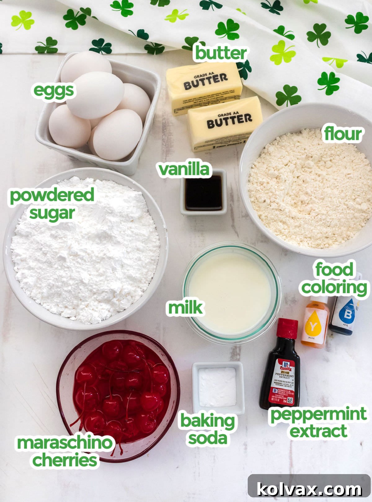 A beautifully arranged selection of all the essential ingredients for baking Shamrock Shake Cookies, including fresh butter, powdered sugar, eggs, vanilla extract, peppermint extract, all-purpose flour, baking soda, milk, and vibrant food coloring.