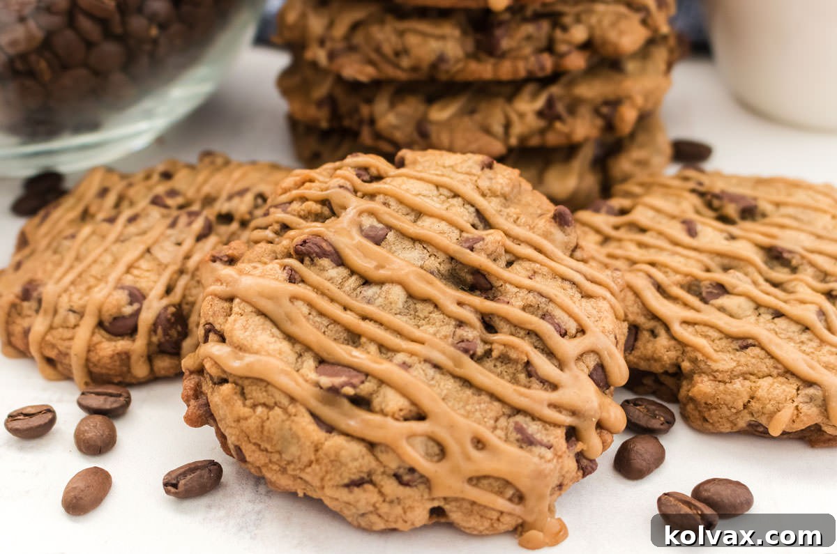 Close up on a stack of three Coffee Chocolate Chip Cookies laying on a white table next to a glass bowl filled with coffee beans, highlighting their golden edges and delicious coffee icing drizzle.