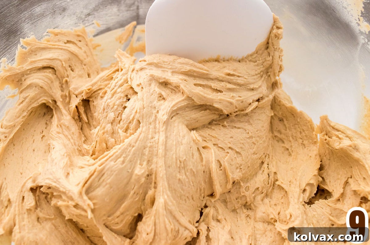 Velvet Coffee Buttercream 6 A close-up view of rich, creamy coffee frosting in a clear glass bowl, with a white spatula resting inside, ready for tasting and use.