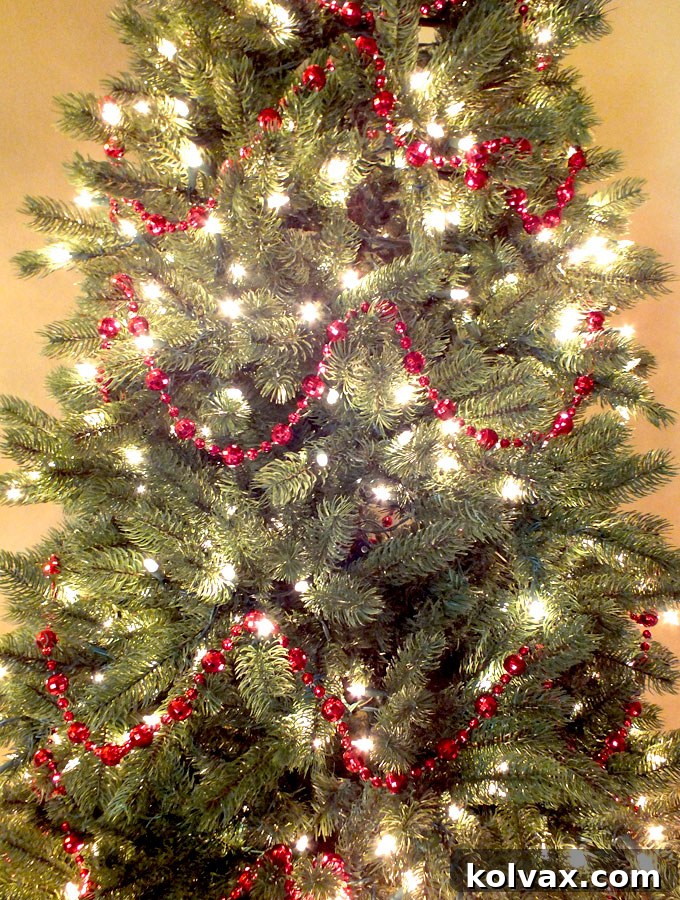 Red beaded garlands elegantly draped around a Christmas tree, providing a vibrant base for further decorations.