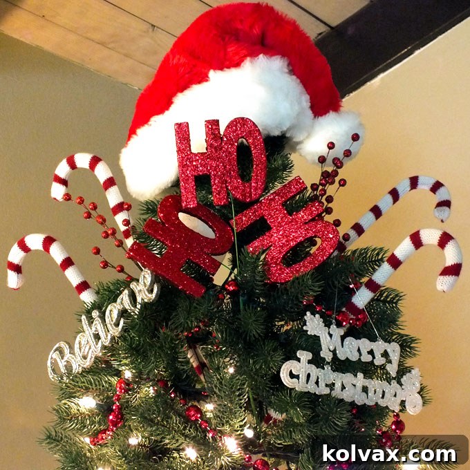 A creative Santa Hat tree topper, adorned with candy canes and a 'Ho, Ho, Ho' sign, crowning a festive Christmas tree.