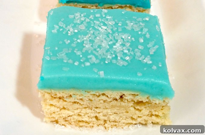 Decorating Frozen Sugar Cookie Bars with blue buttercream frosting and sparkling white sugar sprinkles.