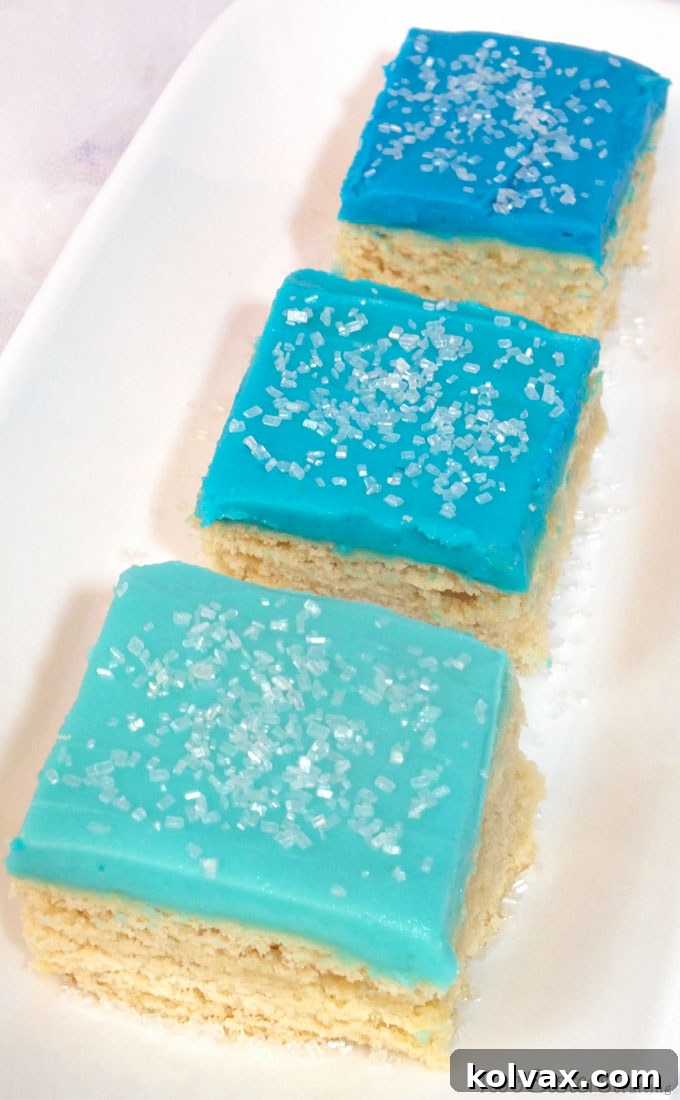A stunning close-up of Frozen Sugar Cookie Bars, showcasing the gradient blue frosting and sparkling white sugar, ready for a party.