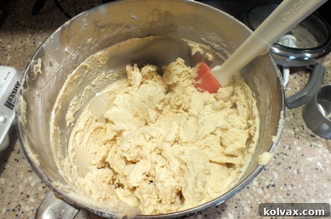 Adding dry ingredients like flour and baking powder to the wet mixture to form the Frozen Sugar Cookie Bar dough.
