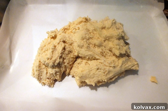 Spreading all of the sticky Frozen Sugar Cookie bar dough onto a large cookie sheet lined with parchment paper for even baking.