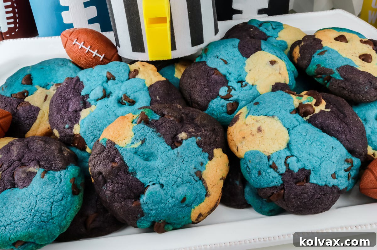 A close-up shot of several Carolina Panthers-themed chocolate chip cookies arranged on a white serving platter, showcasing their blue, black, and white marbled colors with visible chocolate chips.