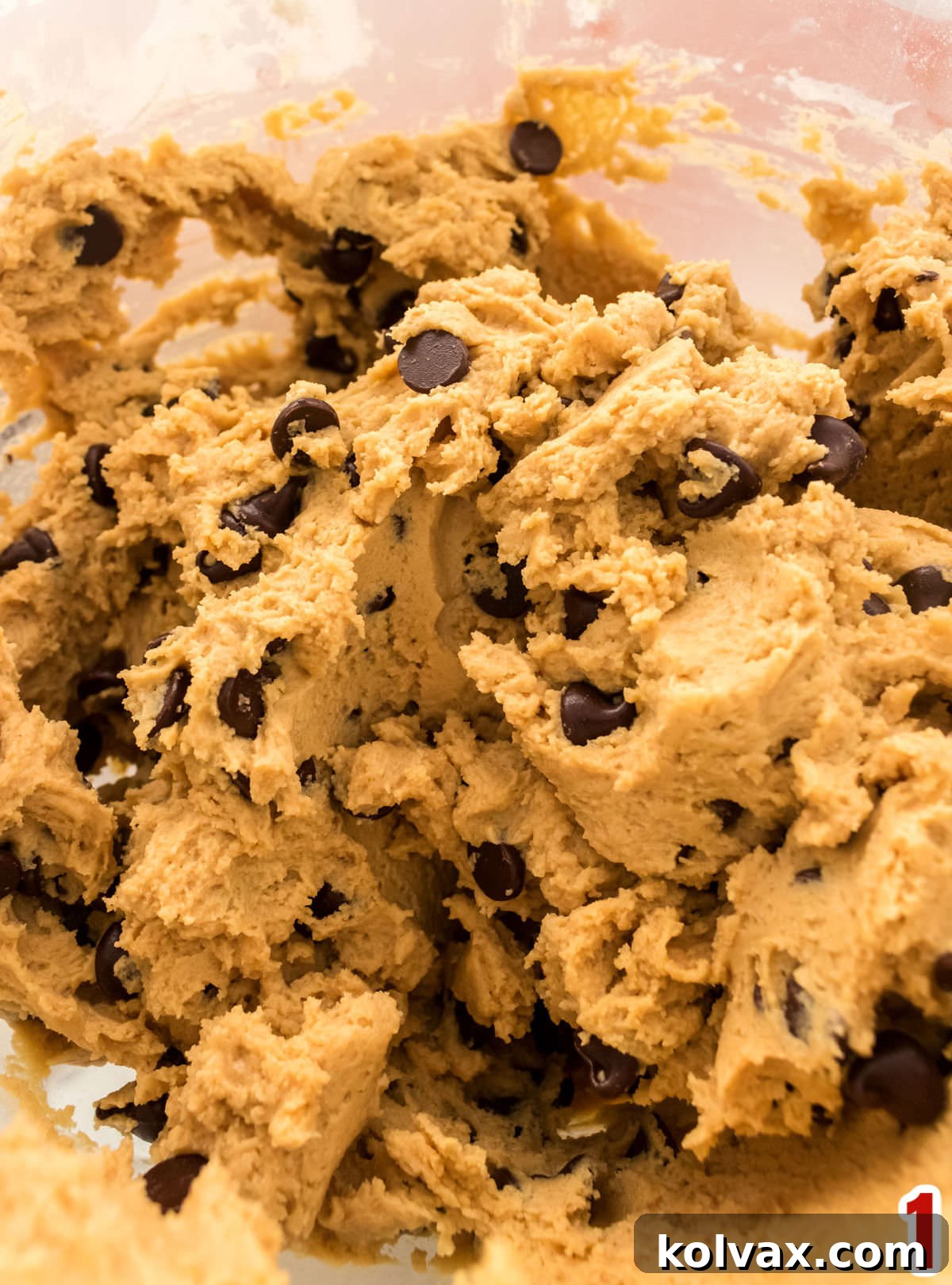 Closeup on a clear glass bowl filled with Peanut Butter Chocolate Chip cookie dough.