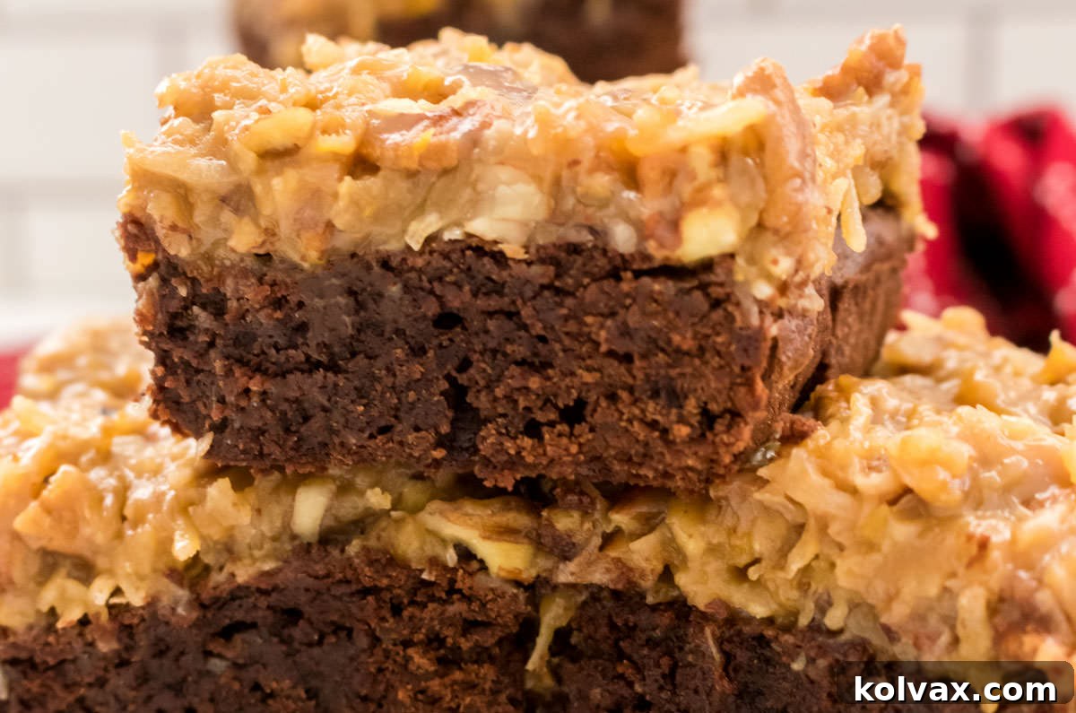 Three decadent German Chocolate Brownies stacked neatly, showcasing the rich chocolate base and abundant coconut pecan frosting, set against a rustic red kitchen towel.