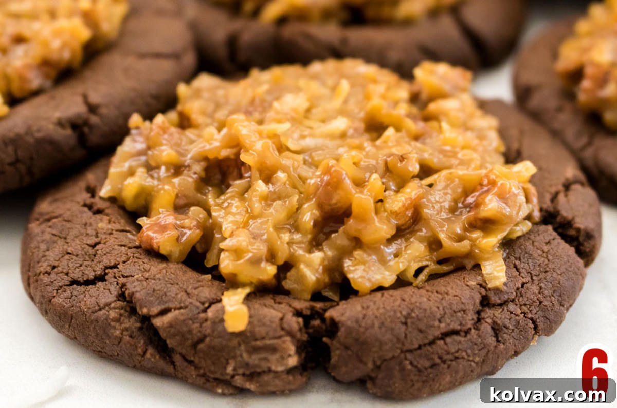 A close-up shot of a single German Chocolate Cookie with its generous dollop of coconut pecan frosting, resting on a clean white surface.