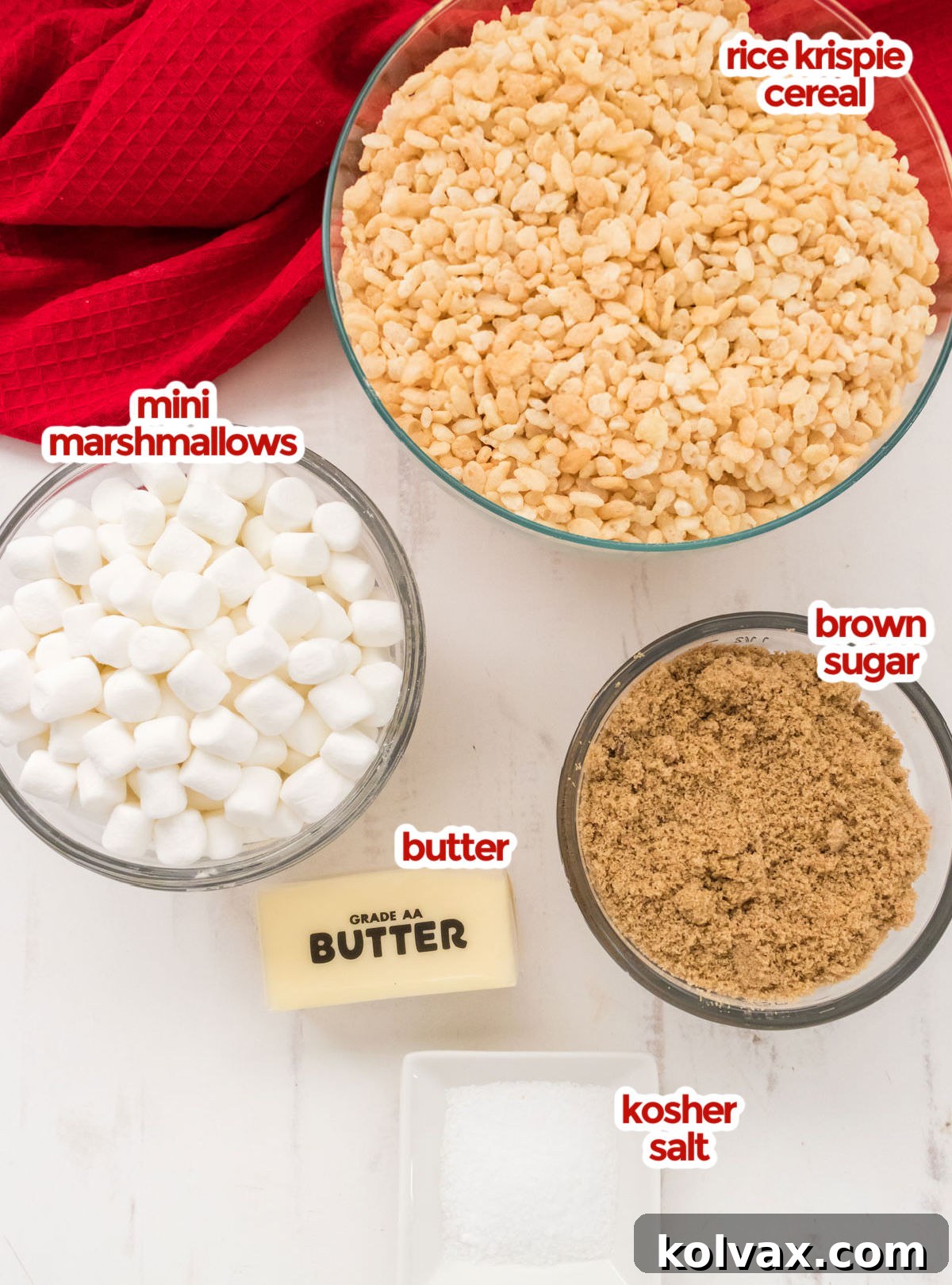 Salted Caramel Krispie Bliss 3 All the core ingredients laid out on a rustic wooden board: a generous bowl of Rice Krispie Cereal, a large bag of mini marshmallows, a measuring cup of packed brown sugar, a stick of butter, and a small dish of Kosher salt. Each ingredient is perfectly portioned and ready for use.