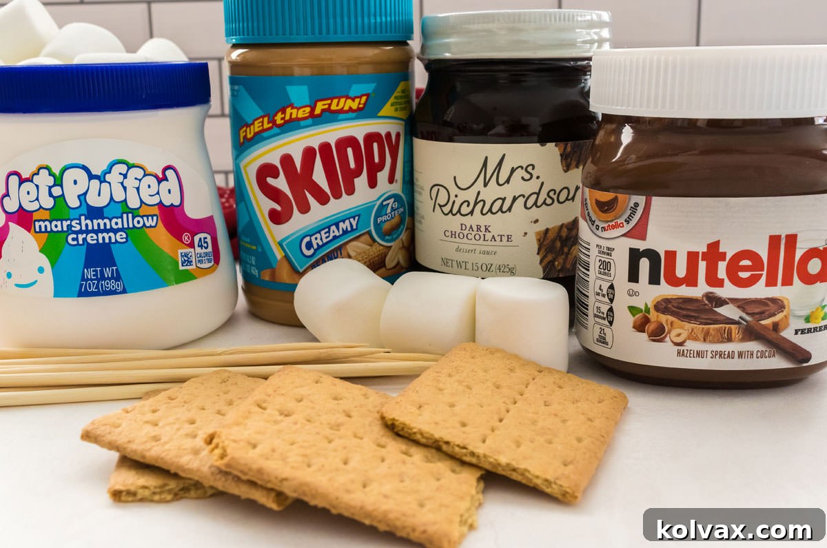 Jars of gourmet sauces including Marshmallow Creme, creamy Peanut Butter, rich Chocolate Sauce, and smooth Nutella, arranged with graham crackers and marshmallows on a white table.