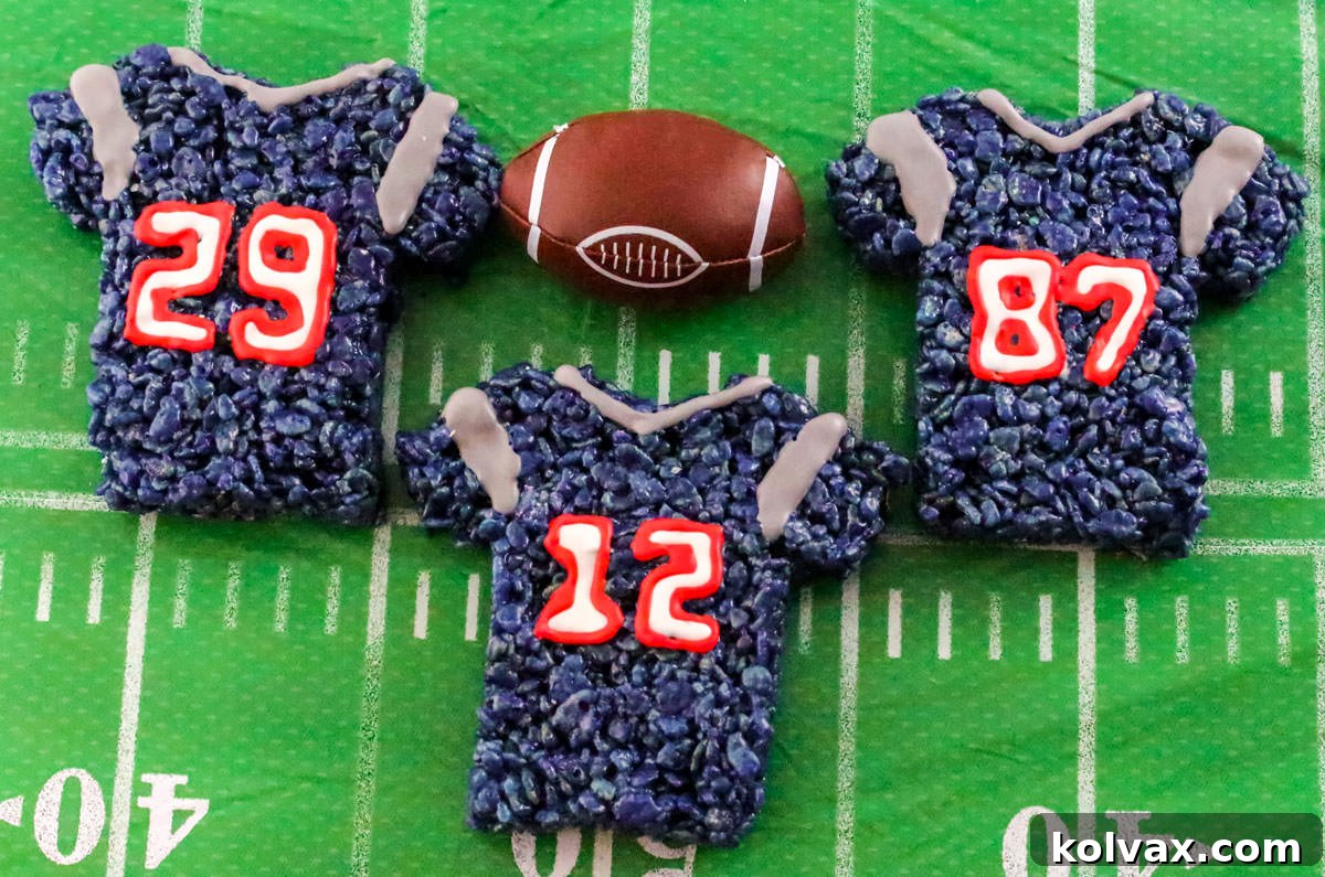 Three New England Patriots Rice Krispie Treats laying on a football table cloth.
