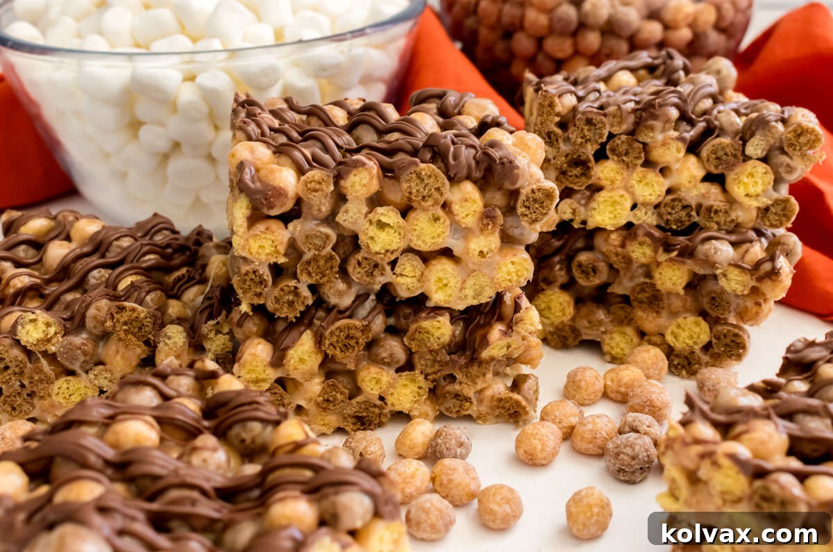 A batch of golden Reese's Puffs Marshmallow Treats on a white table, with bowls of cereal and marshmallows in the background, hinting at the delicious ingredients.
