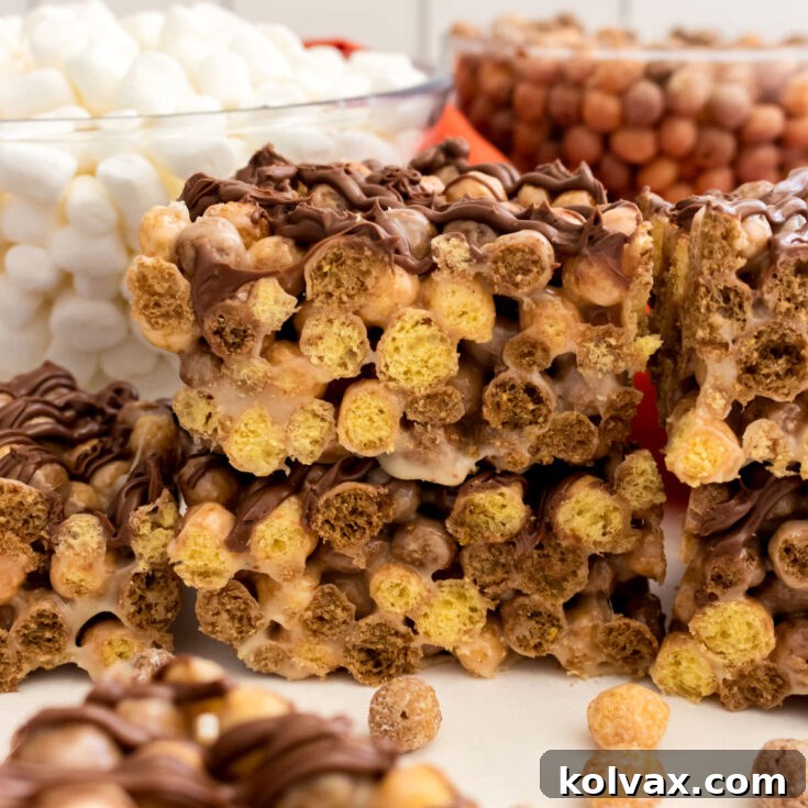 A batch of Reese's Puffs Marshmallow Treats sitting on a white table in front of clear bowls filled with marshmallows and cereal.