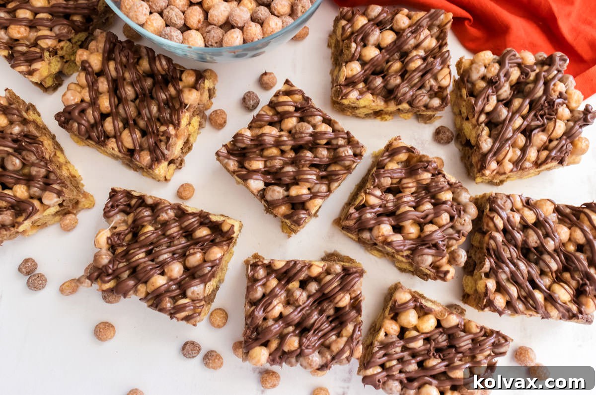 An overhead shot of a fresh batch of Reese's Puffs Marshmallow Treats, surrounded by loose cereal and a vibrant orange kitchen towel on a white surface, invitingly ready to be served.