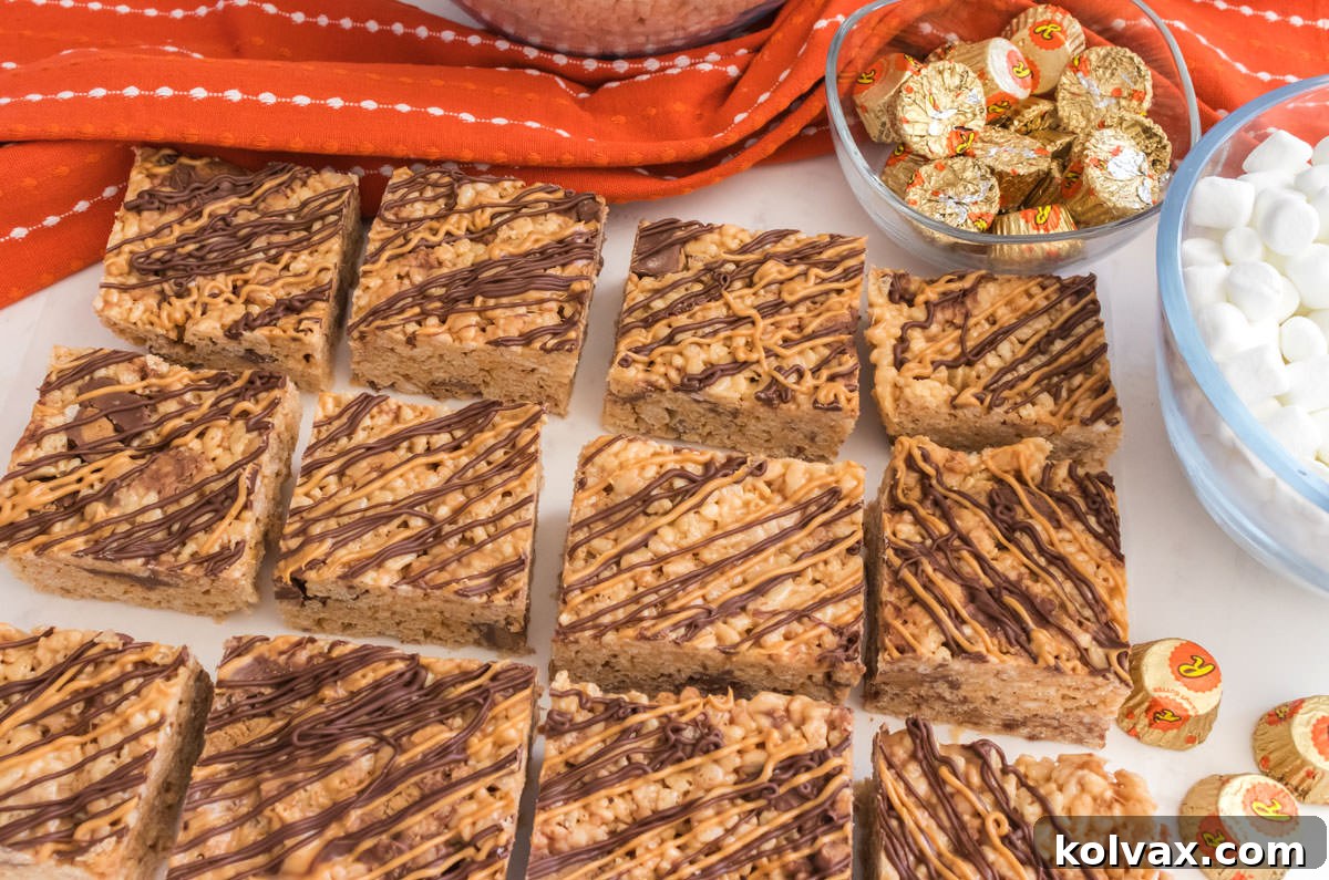 An overhead shot of a batch of freshly made Peanut Butter Cup Rice Krispie Treats lying on a white table with an orange kitchen towel, ready for serving.