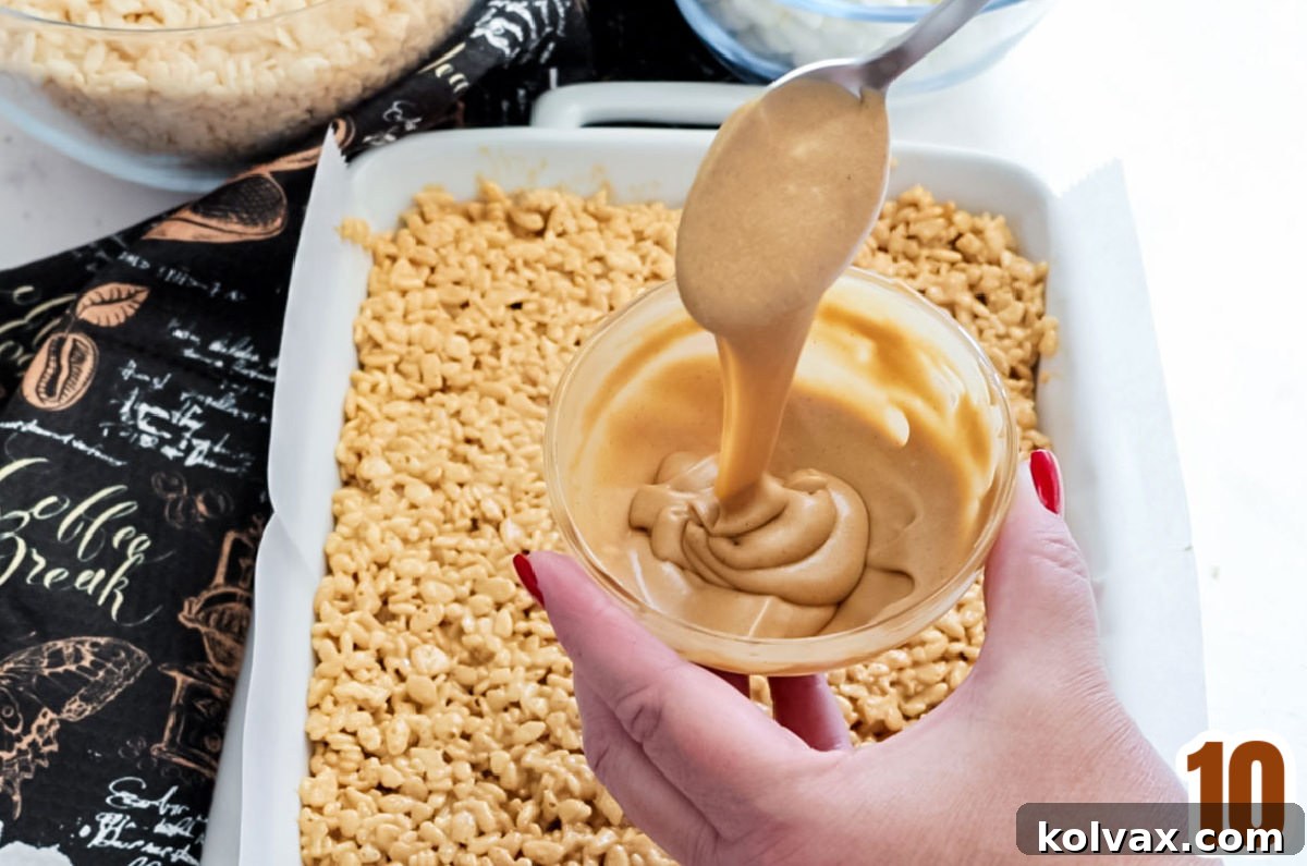 A small bowl of freshly made coffee icing positioned above a pan filled with cooling Coffee Rice Krispie Treats, ready for drizzling.