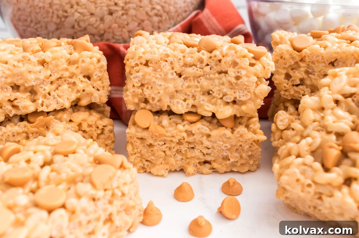 A batch of golden Butterscotch Rice Krispie Treats sitting on a pristine white table, surrounded by scattered butterscotch chips and ready to be enjoyed.