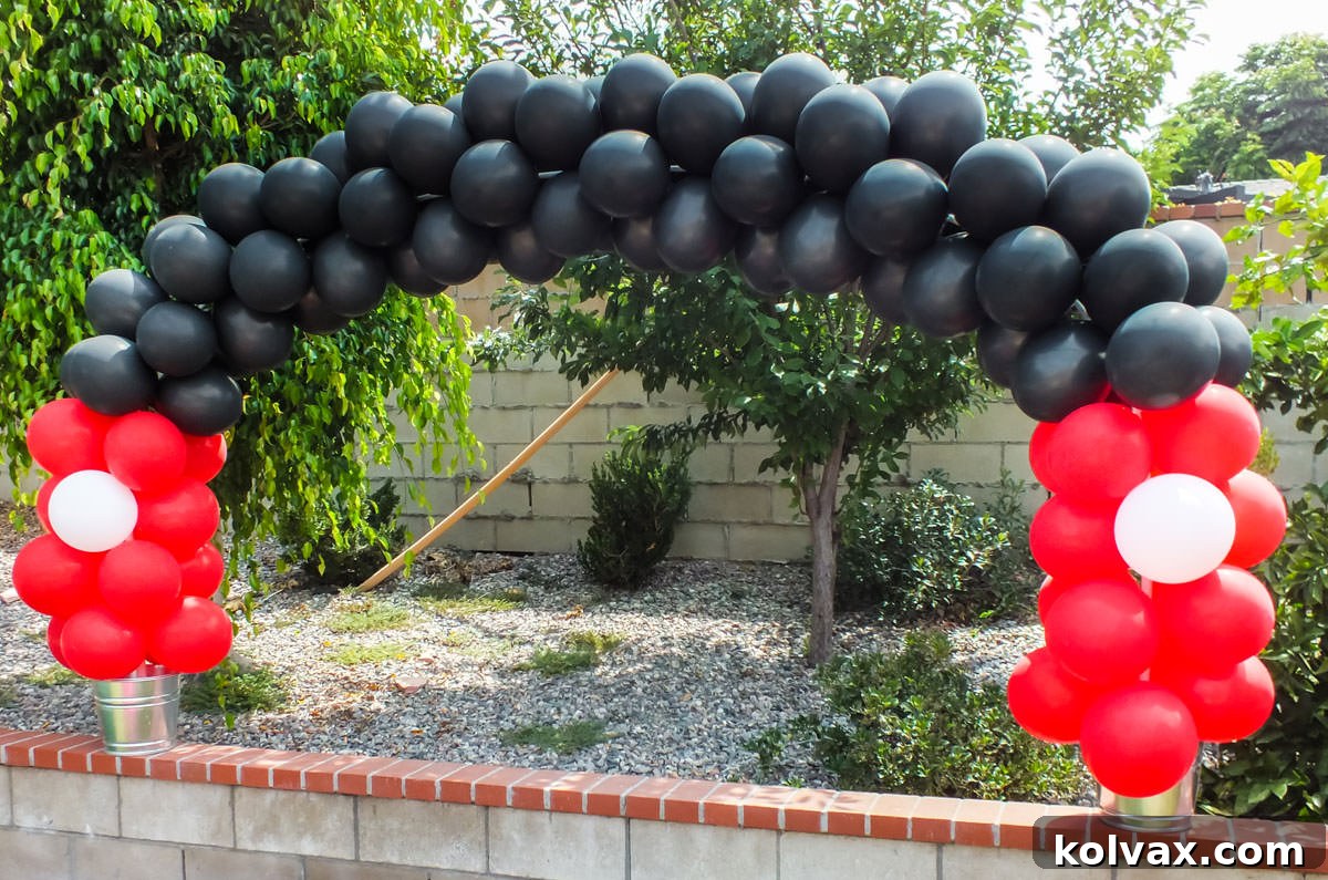 Mickey Mouse themed balloon arch in red, black, and white, creating a welcoming entrance.