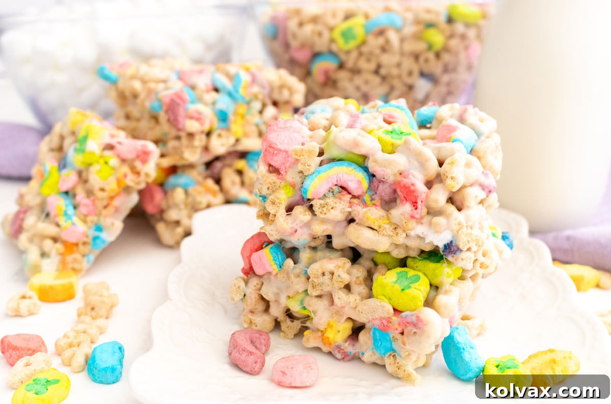 Charmed Marshmallow Delights 2 A batch of Lucky Charms Marshmallow Treats sitting on a white table next to a glass of milk.