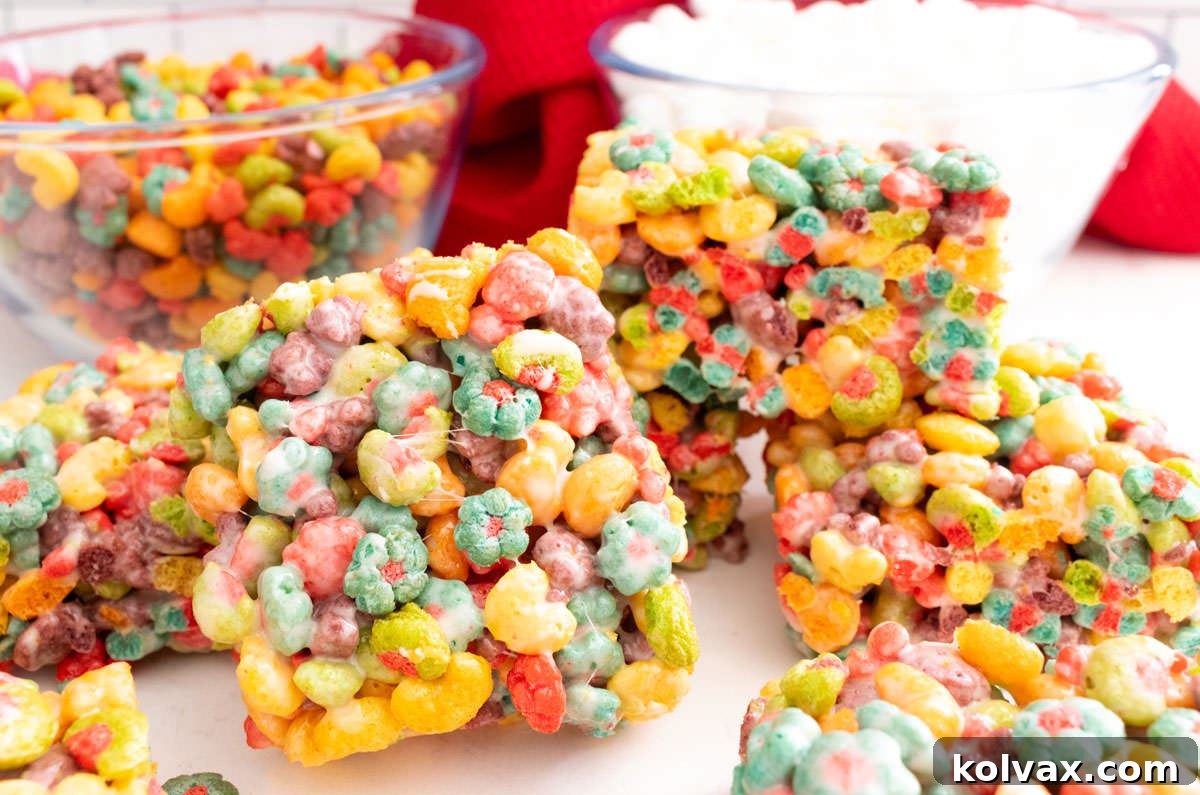 Trix Fruity Marshmallow Squares 2 A vibrant batch of Trix Marshmallow Treats on a white table with a red kitchen towel in the background, showcasing their irresistible colors.