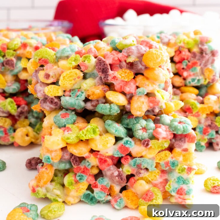 Trix Fruity Marshmallow Squares 8 A closeup of a stack of two Trix Marshmallow Treats, beautifully displaying their colors, next to bowls of Trix cereal and mini marshmallows.