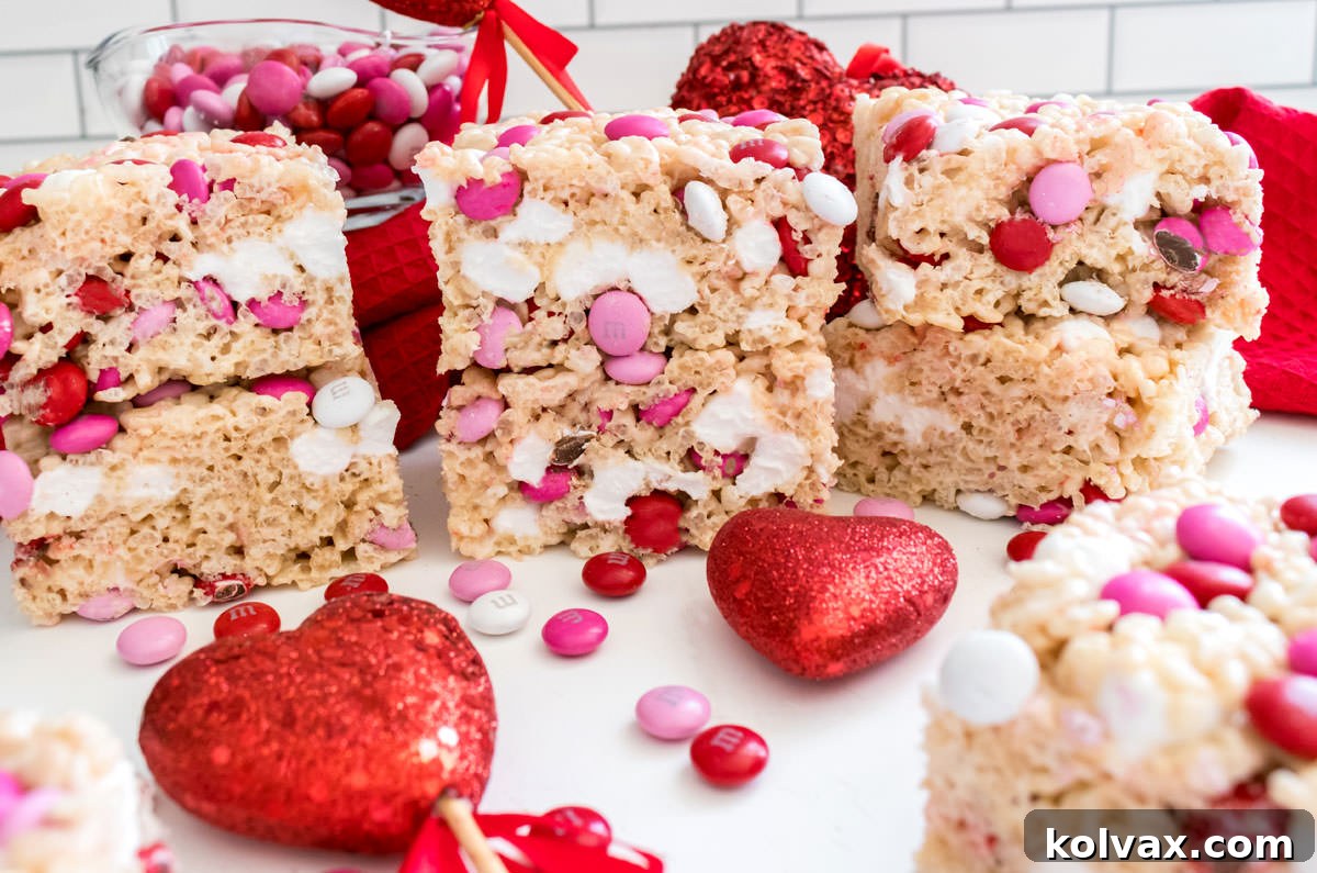 Sweetheart M&M Rice Krispie Bars 2 A vibrant batch of Valentine's Day M&M Rice Krispie Treats on a white table, surrounded by festive red, pink, and white M&M's and heart-shaped candies, ready for sharing.