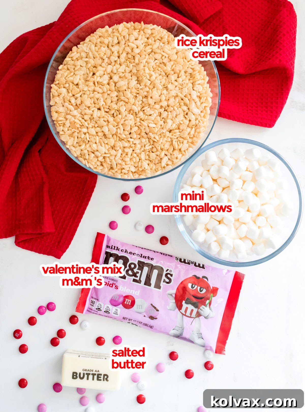Sweetheart M&M Rice Krispie Bars 3 All the essential ingredients neatly laid out for crafting delightful Valentine's Day M&M Rice Krispie Treats, featuring butter, mini marshmallows, crisp Rice Krispies cereal, and a colorful bag of festive M&M candies.