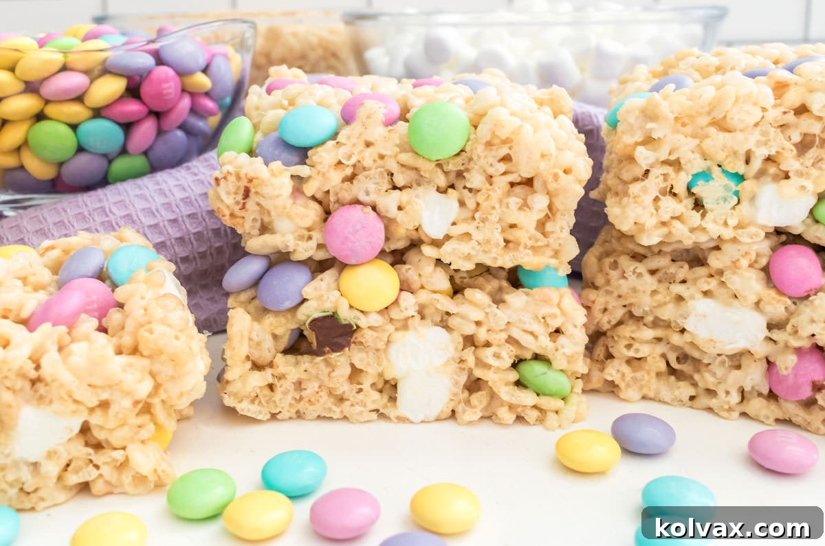 Closeup on a batch of vibrant Springtime M&M Rice Krispie Treats sitting on a white table, surrounded by loose pastel M&M's, creating a festive and inviting scene.