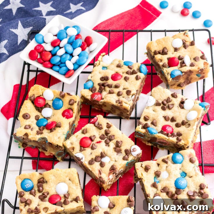 Closeup on a batch of Patriotic M&M Chocolate Chip Cookie Bars laying on a baking cooling rack and an American Flag Kitchen Towel.