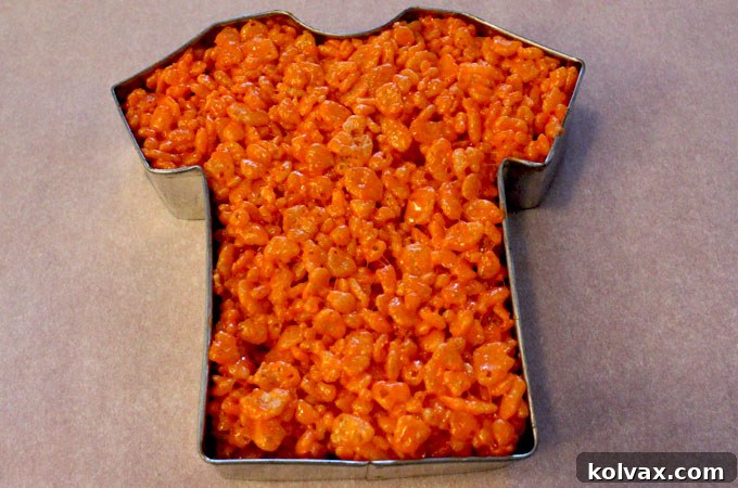 Shaping the orange Rice Krispie Treat mixture into a perfect football jersey using a cookie cutter.