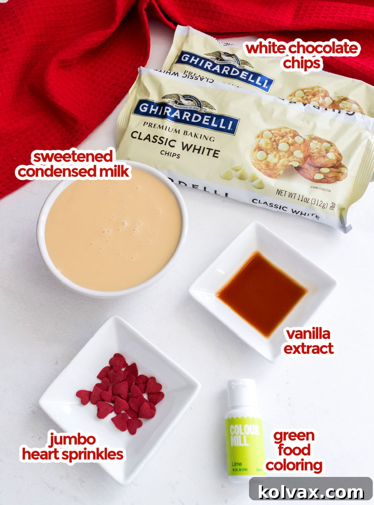 All the essential ingredients neatly laid out to make Easy Grinch Fudge, including bags of white chocolate chips, a can of sweetened condensed milk, a bottle of vanilla extract, and vibrant green food coloring.