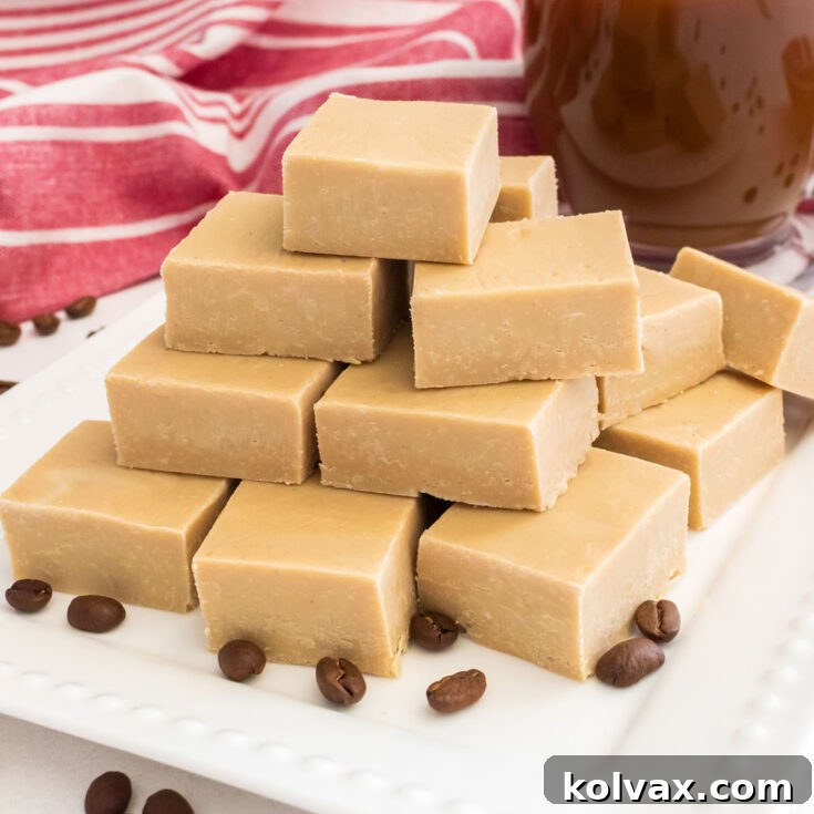 Close up on a stack of Easy Coffee Fudge sitting on a white dessert plate next to a glass mug of coffee, ready to be enjoyed.