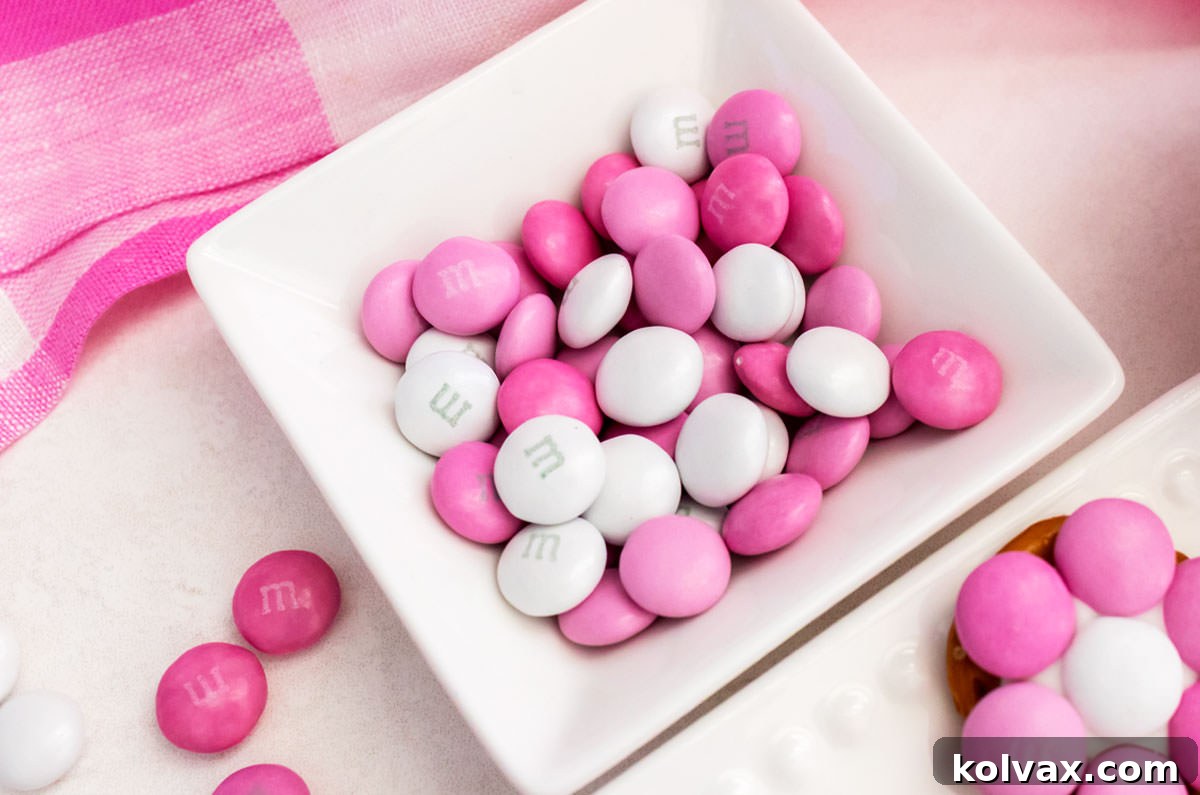 Closeup shot of a small white ramekin filled with a mix of pink and white M&M's, ready for decorating.