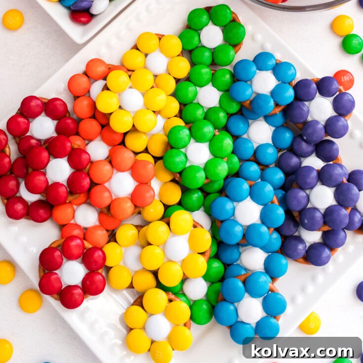 Closeup overhead shot of a batch of Over the Rainbow Flower Pretzel Bites on a white dessert plate.